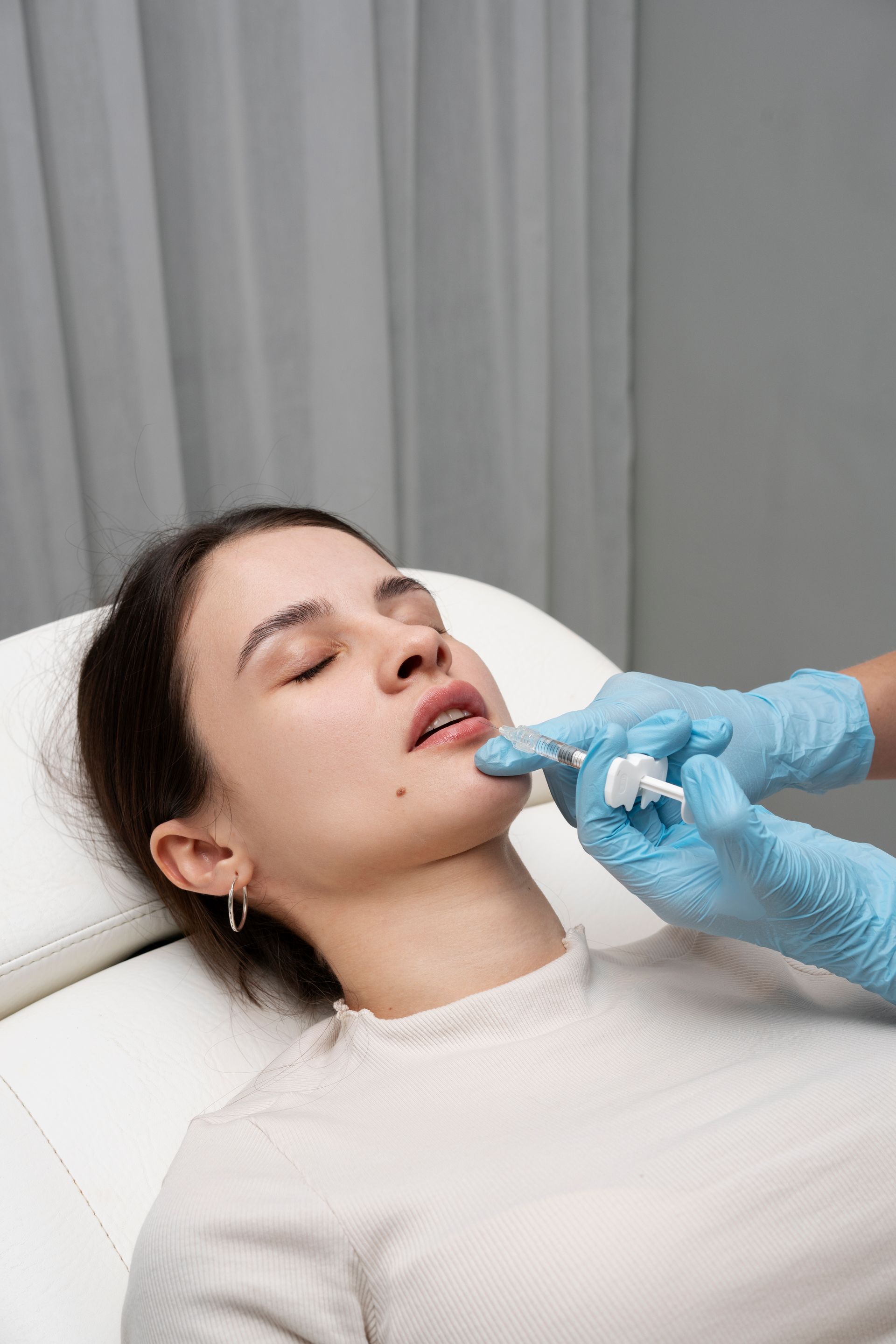 A woman is getting a botox injection in her lip.