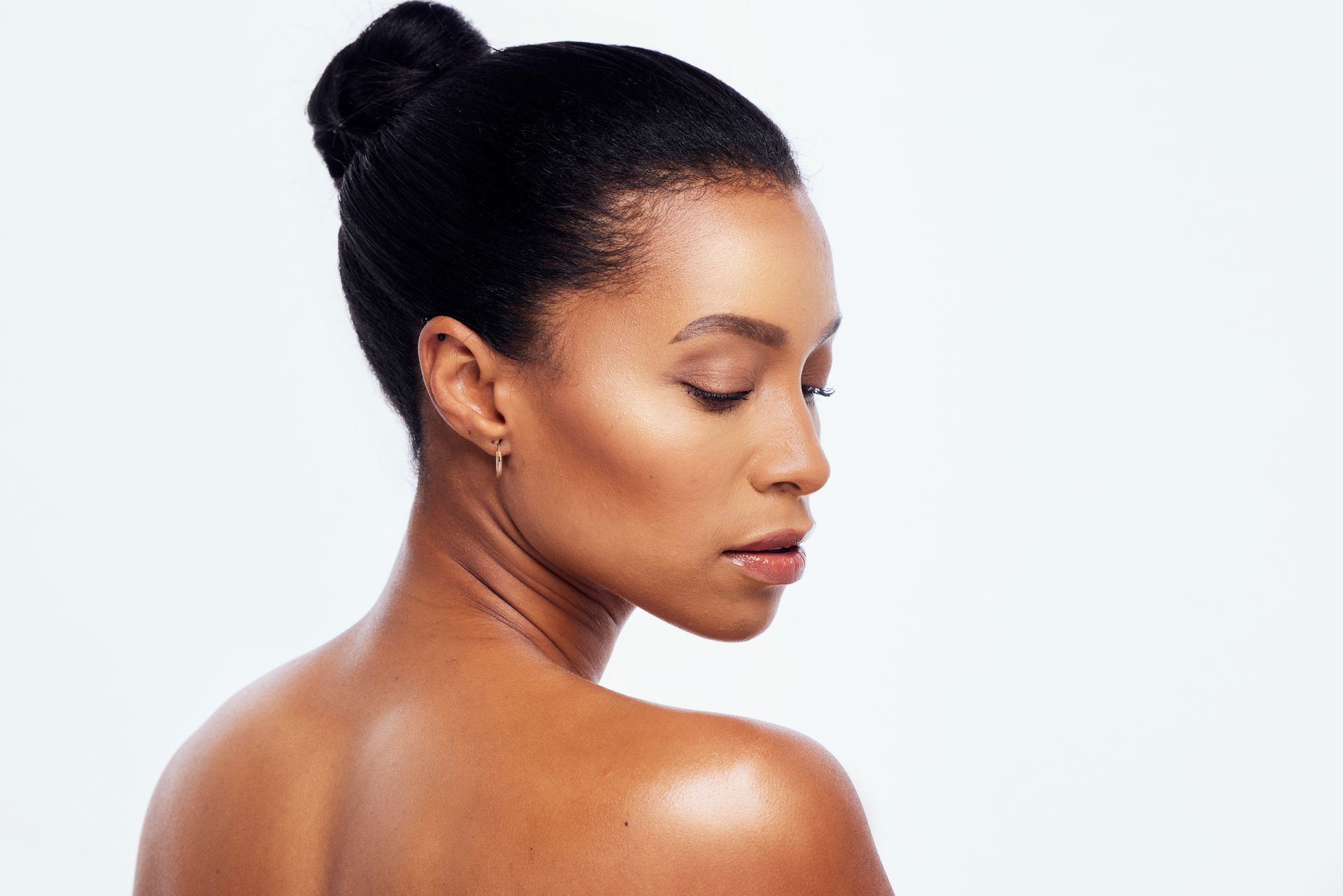 A woman with her hair in a bun is looking over her shoulder.