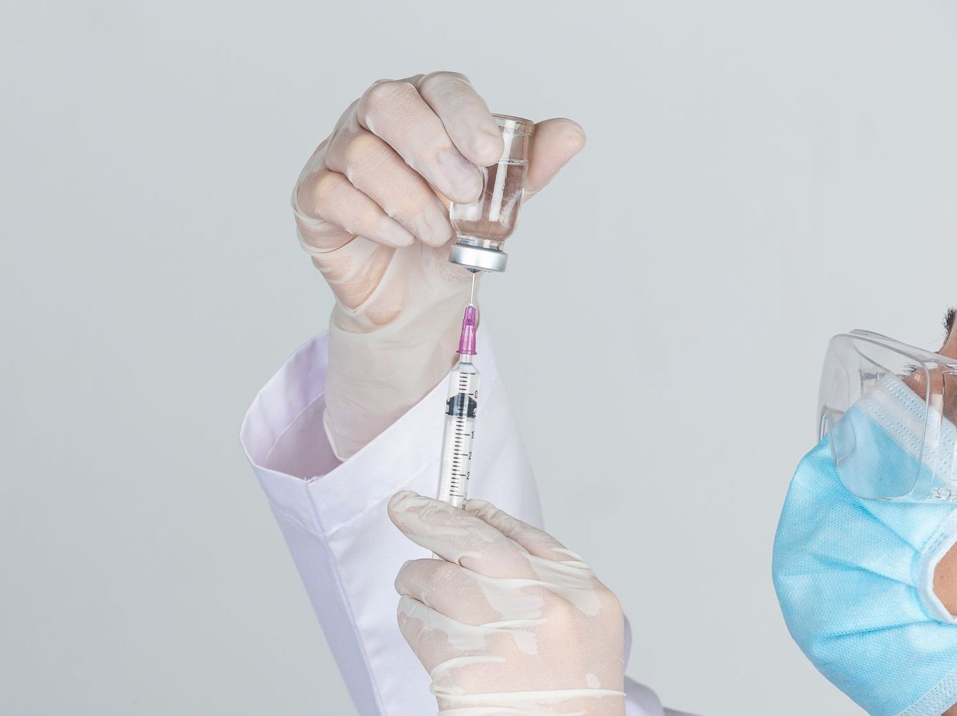 A doctor is preparing an injection with a syringe.