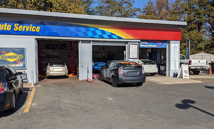 Auto service shop exterior with cars parked outside and one car in a garage bay