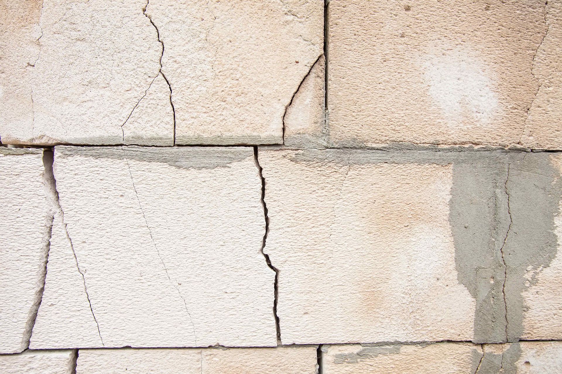 Spiderweb cracks make their way through a brick wall.
