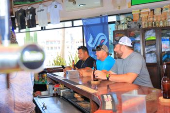 A group of men are sitting at a bar drinking beer.