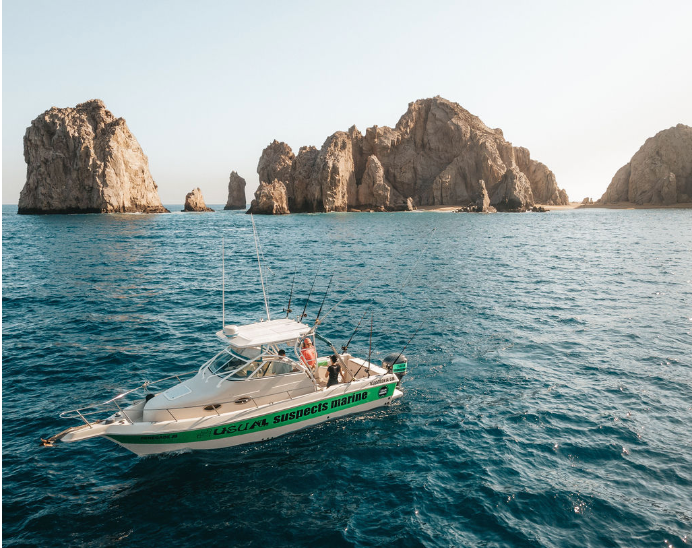 A boat is floating on top of a body of water with rocks in the background.