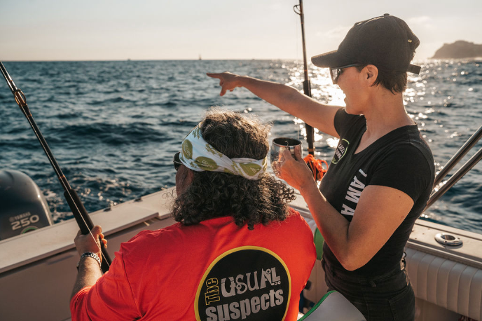 A man and a woman are fishing on a boat in the ocean.