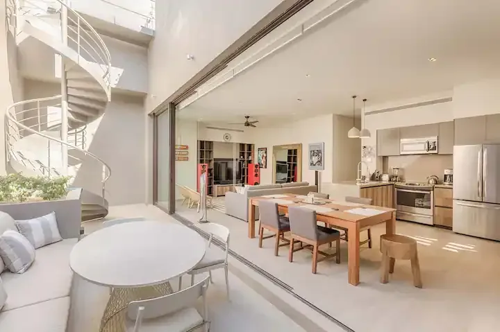 A living room with a dining table and chairs and a spiral staircase.