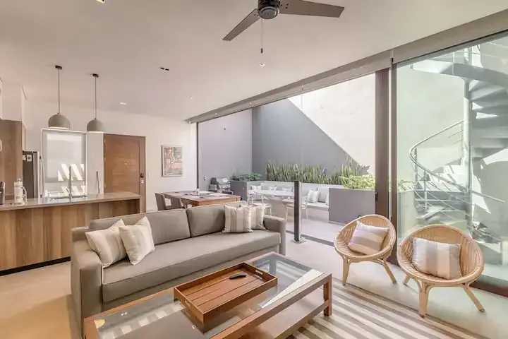 A living room with a couch , chairs , coffee table and ceiling fan.
