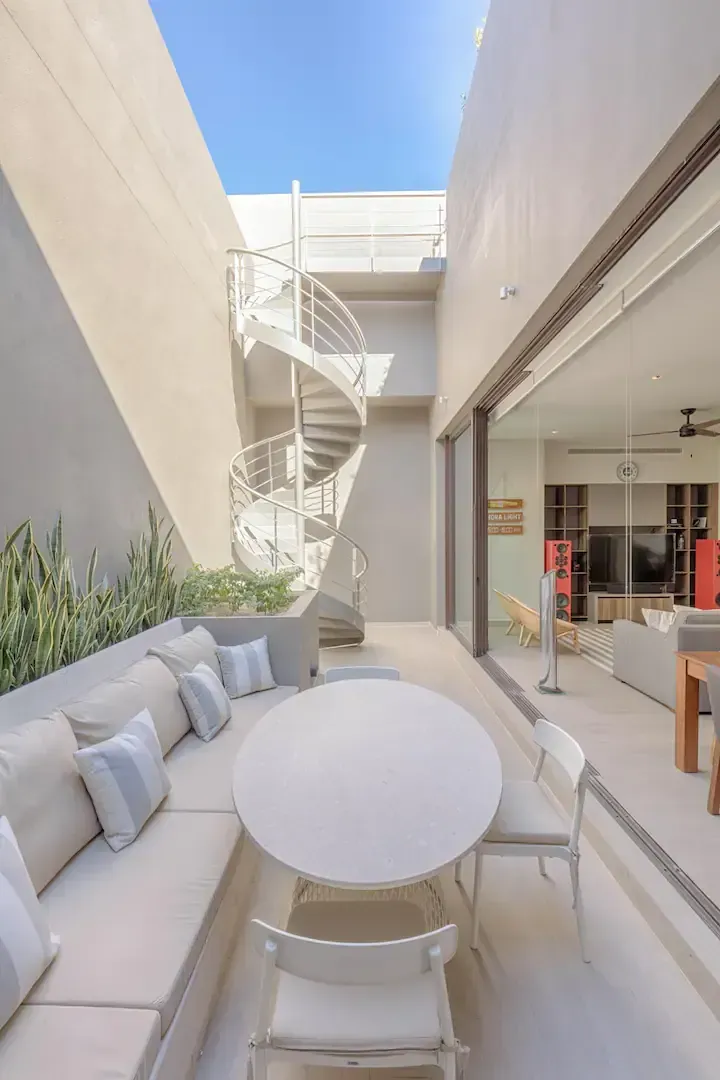 A patio with a table and chairs and a spiral staircase in the background.