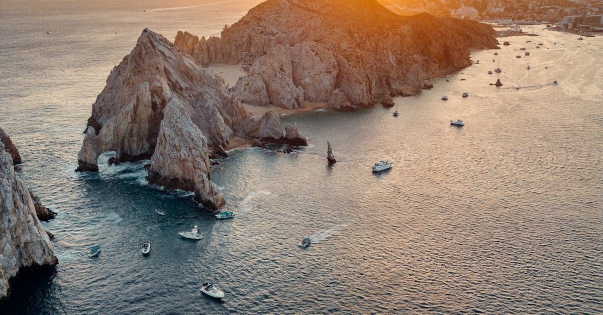 An aerial view of a rocky island in the middle of the ocean with boats in the water.
