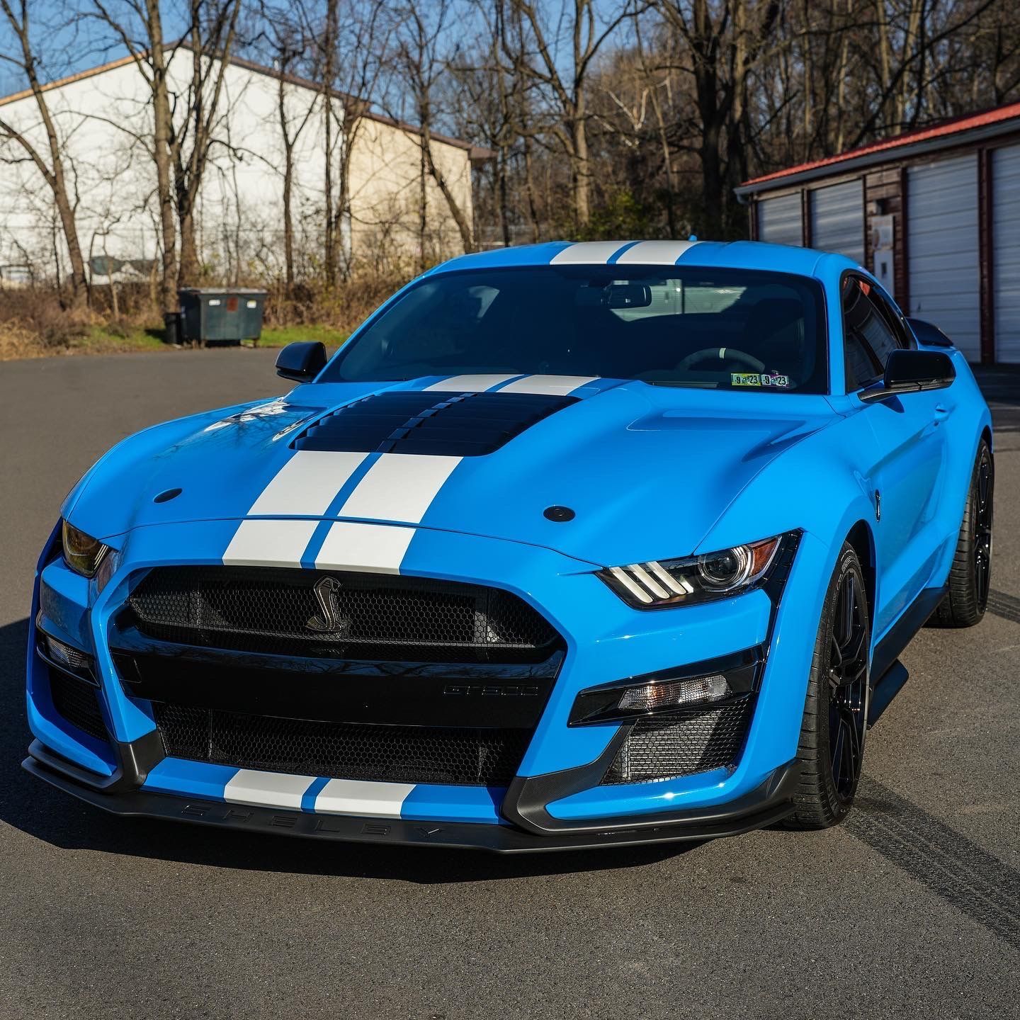 a blue mustang with white stripes is parked in a parking lot