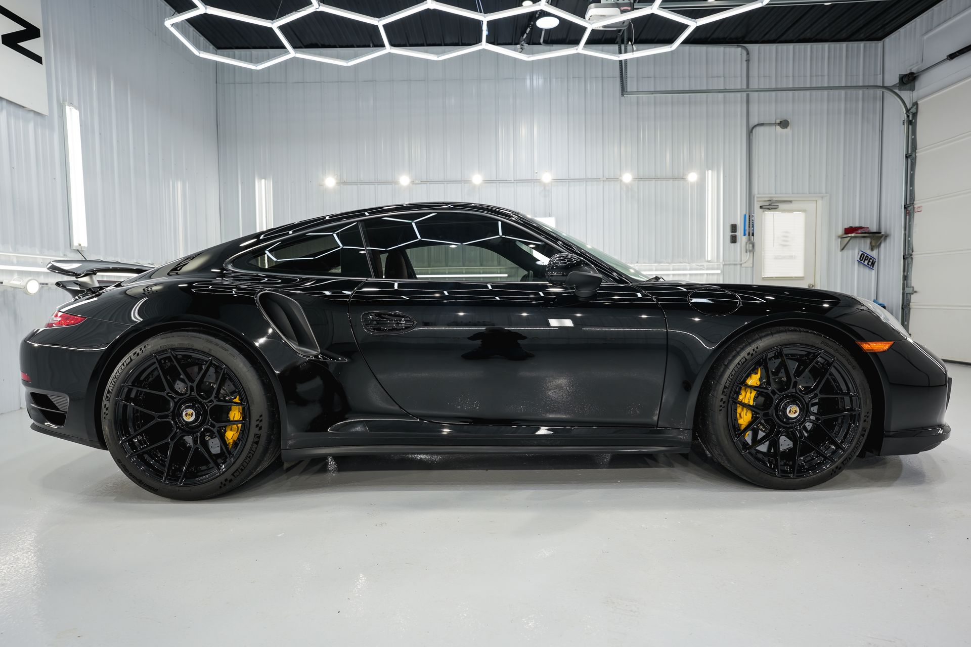 a black porsche 911 turbo s is parked in a garage .