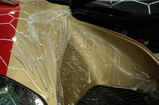 A close up of a car covered in plastic wrap.