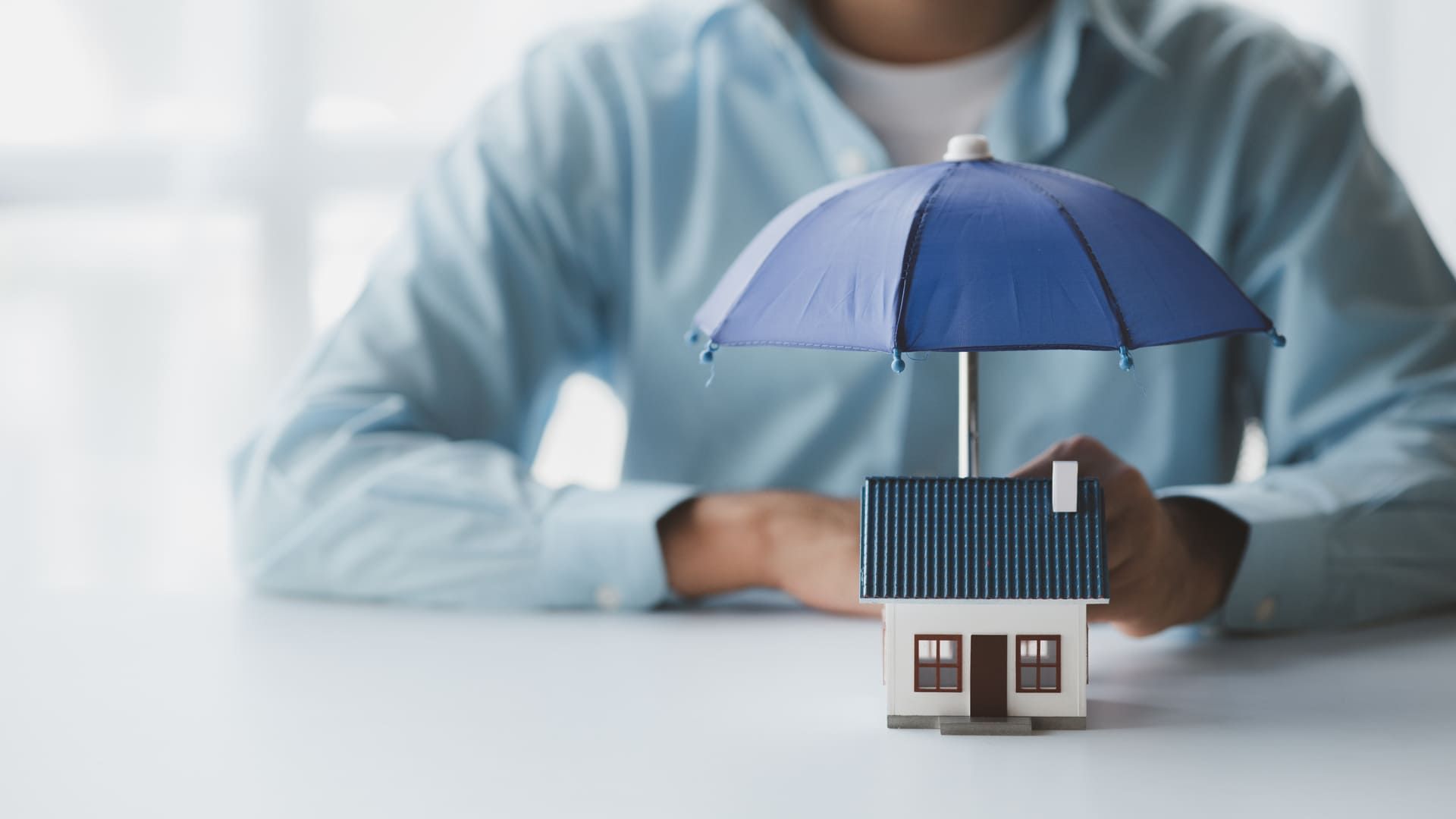 Individuals holding small umbrellas and model homes, housing insurance against impending loss and fire, building fire insurance, home and real estate insurance concepts