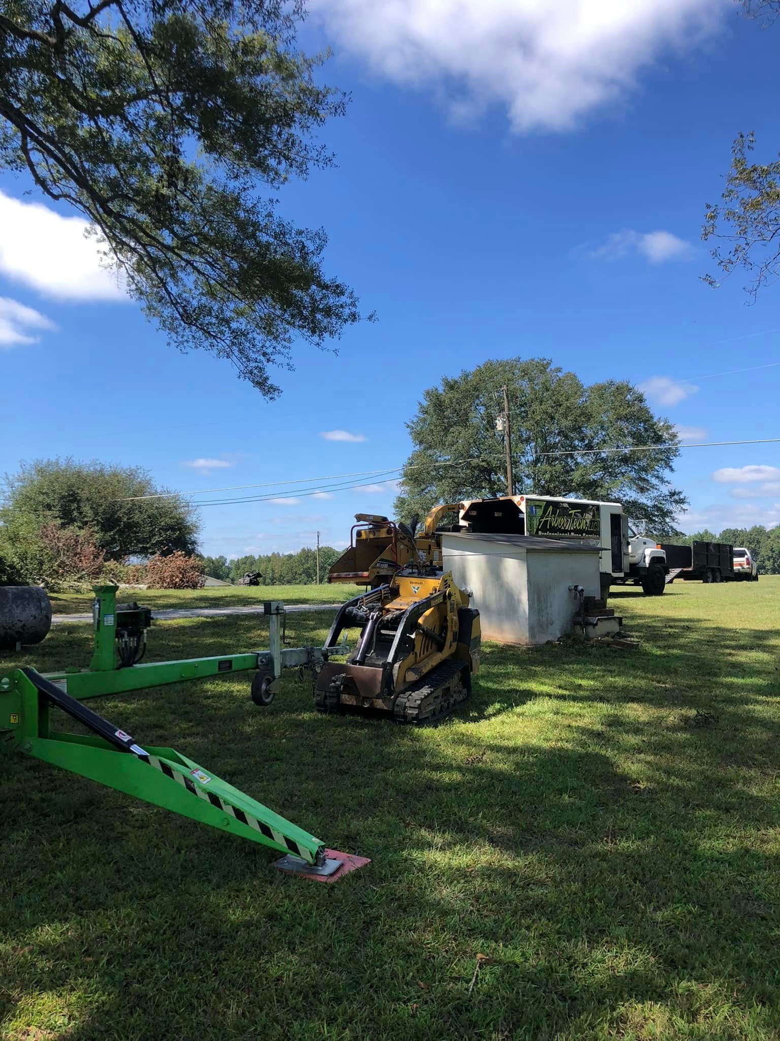 A green trailer is parked in a grassy field next to a truck.