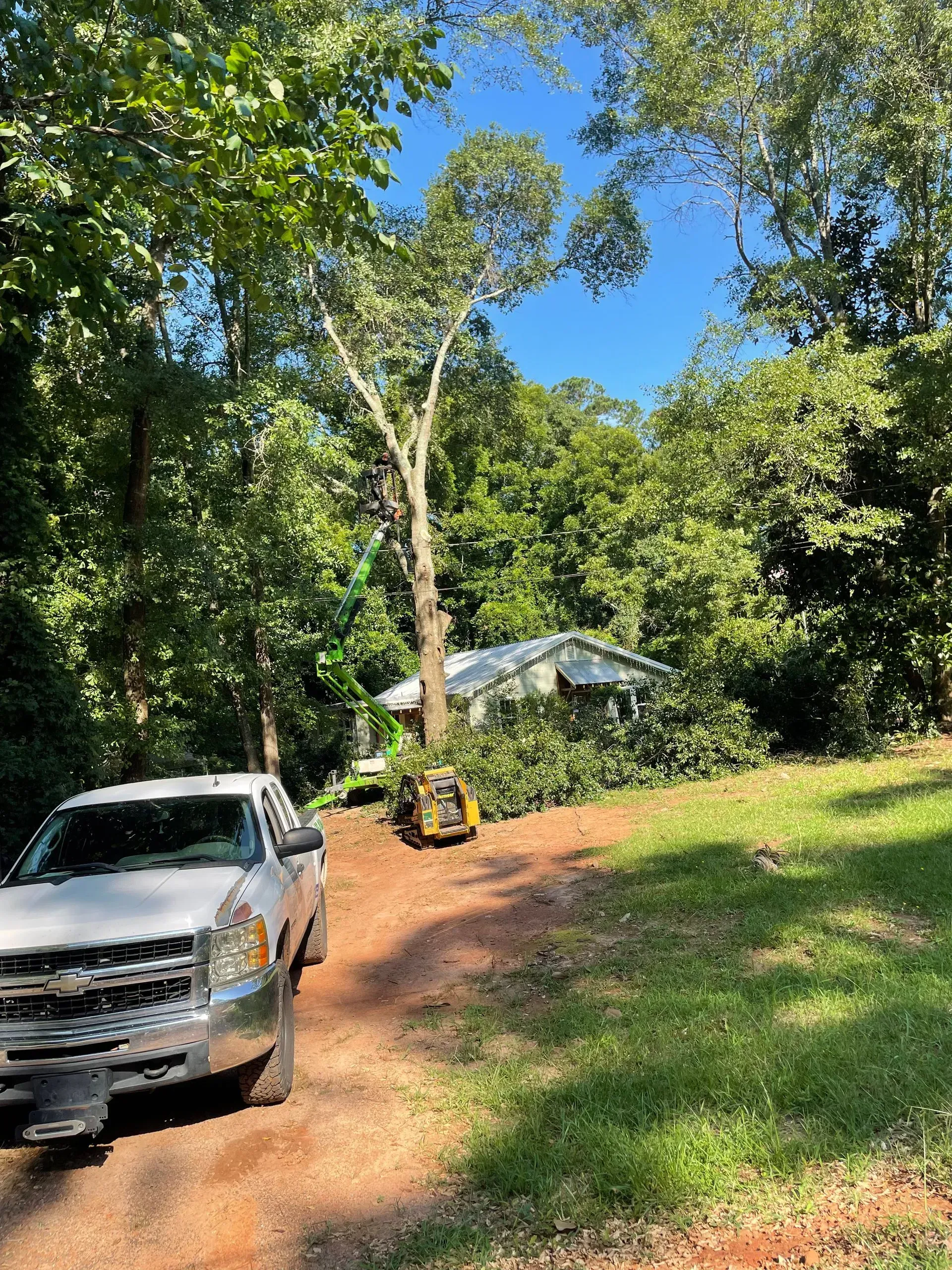 A white truck is parked on a dirt road in front of a house.