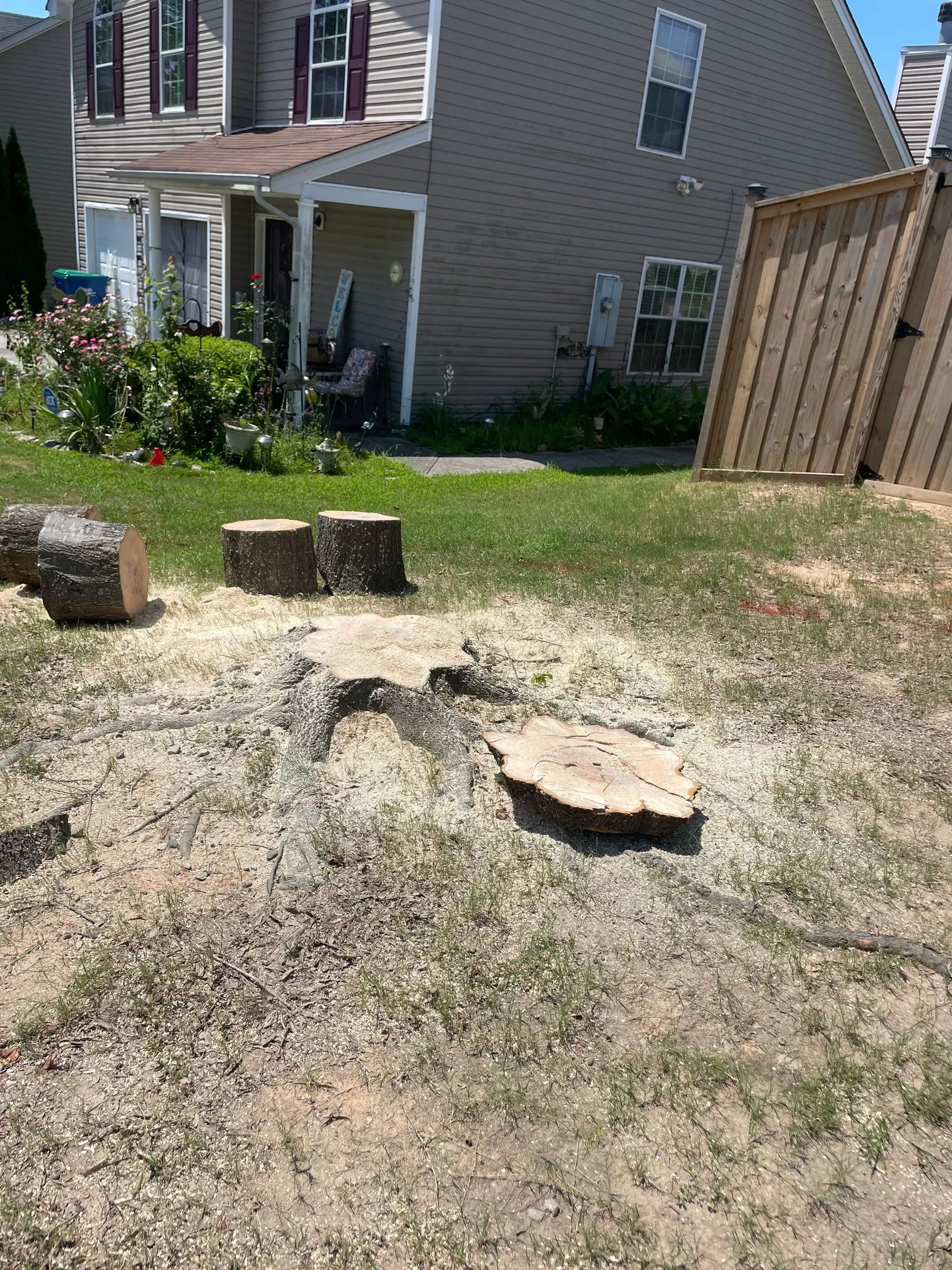 A tree stump is sitting in the grass in front of a house.