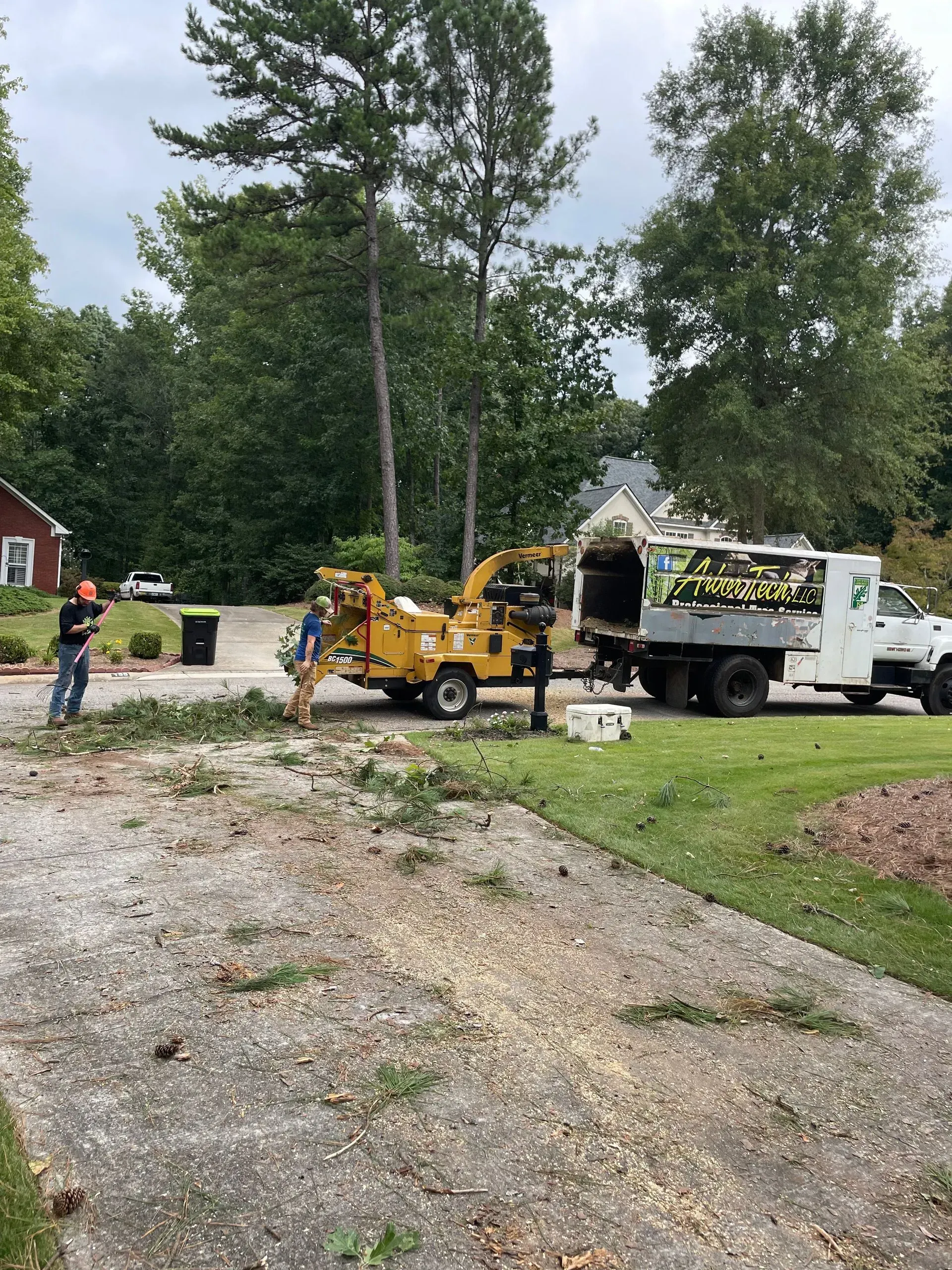 A tree stump grinder is being used to remove a tree stump from a driveway.