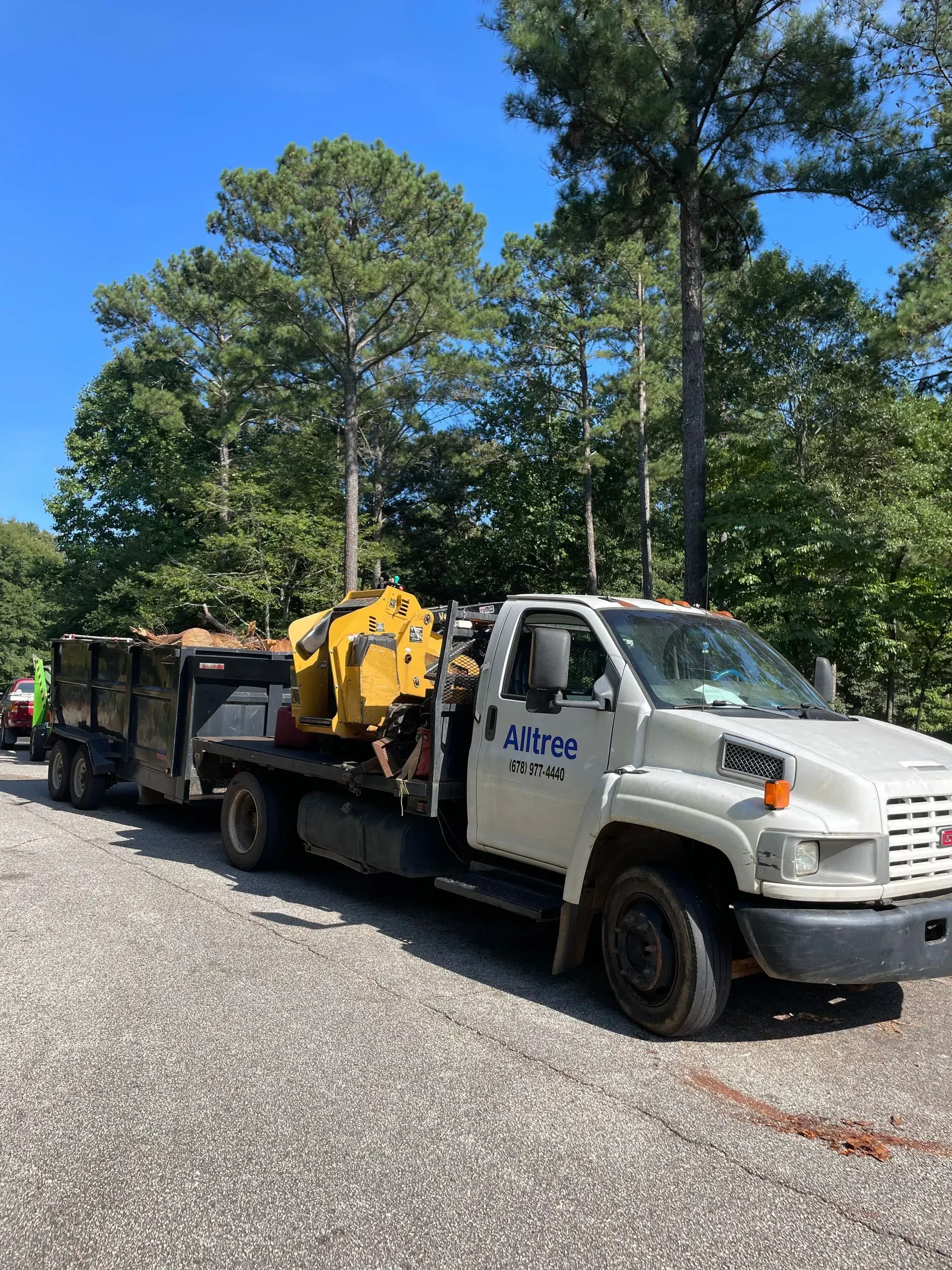 A white truck with a trailer attached to it is parked on the side of the road.