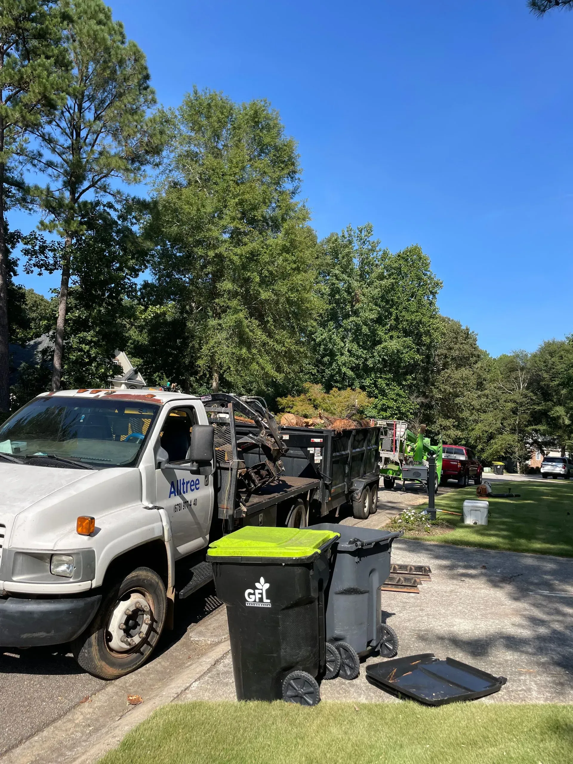 A white truck is parked on the side of the road next to trash cans.