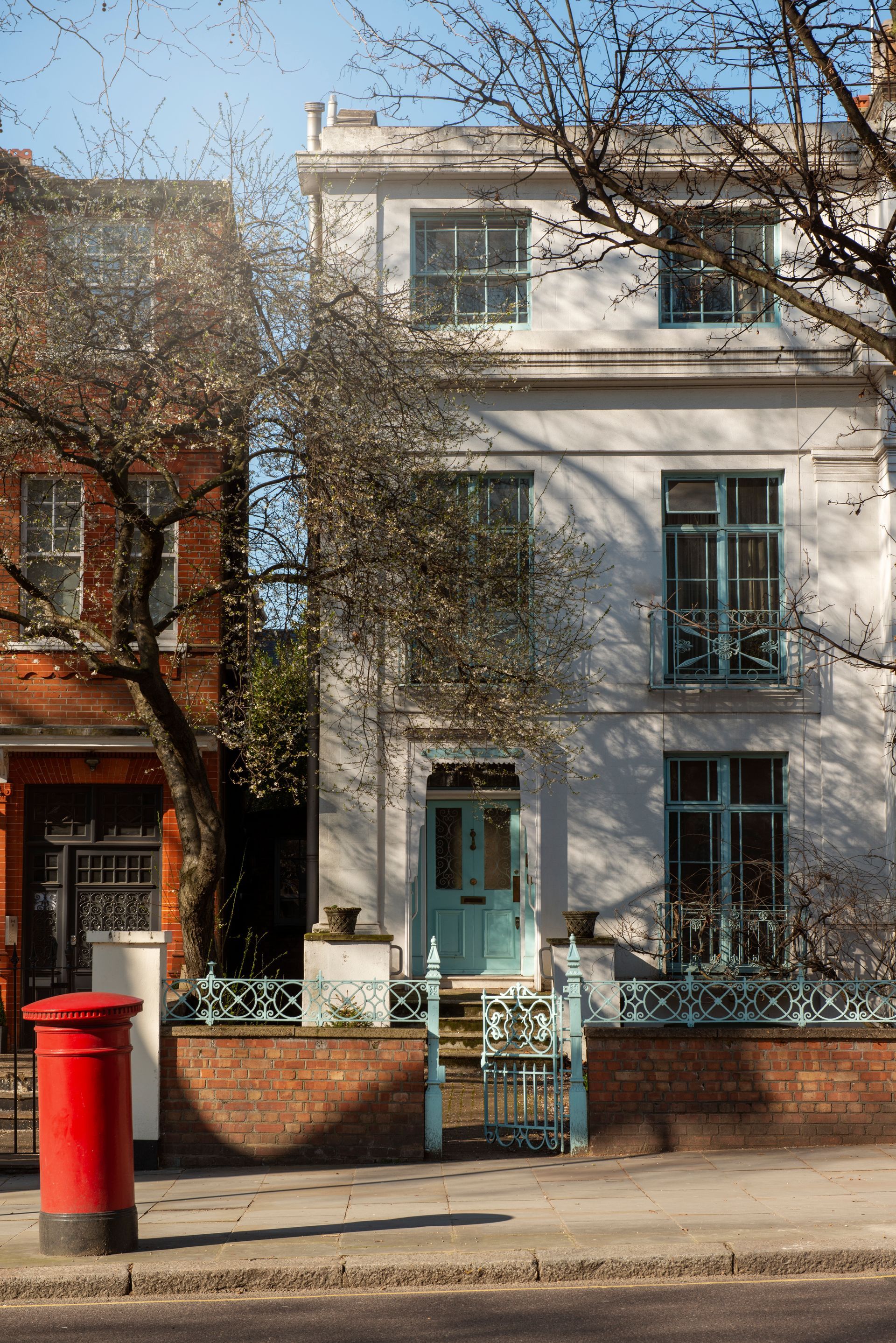 A white house is sitting in the middle of a grassy field surrounded by trees.