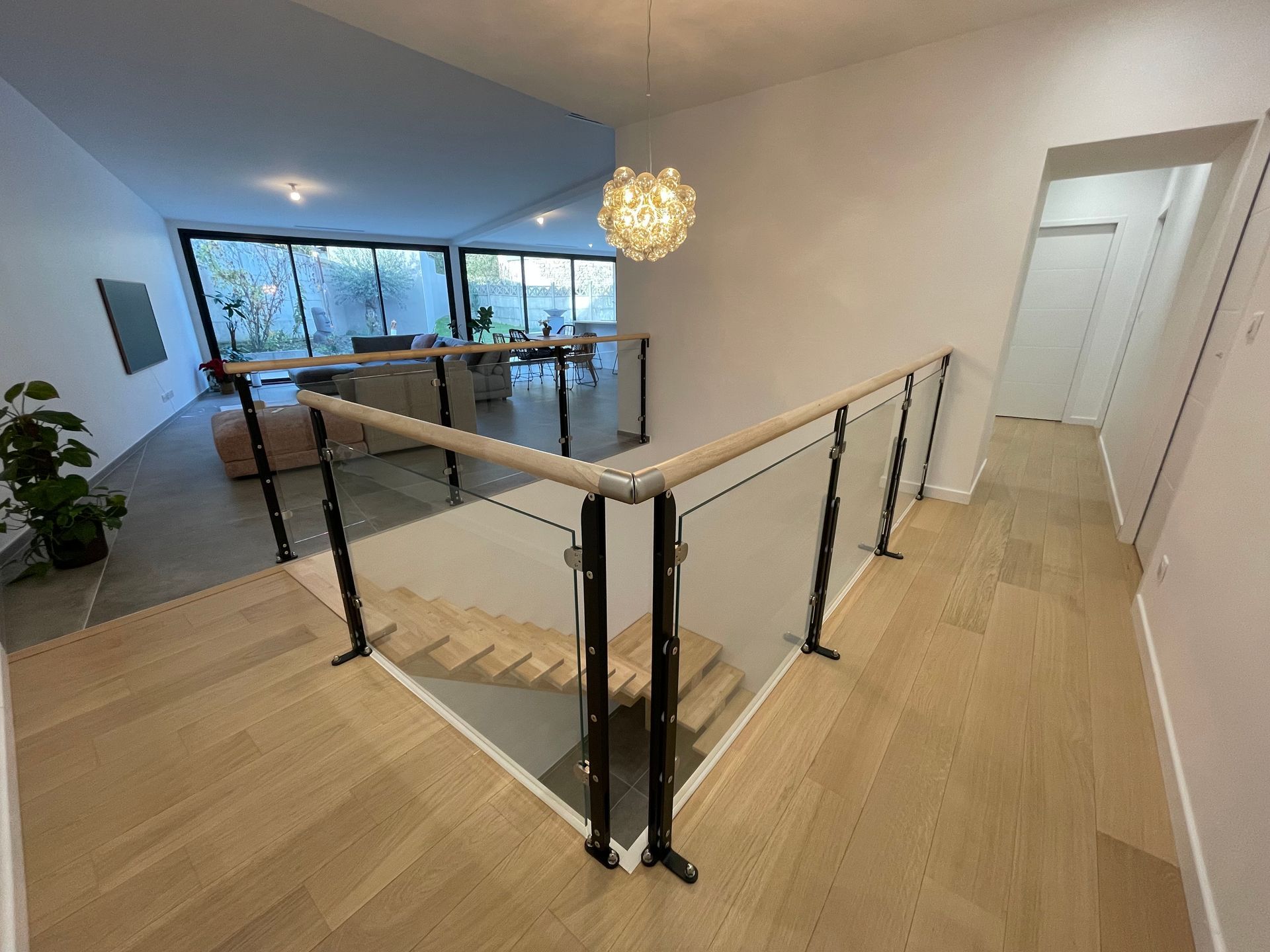 Un escalier avec une rampe en verre menant au deuxième étage d'une maison.
