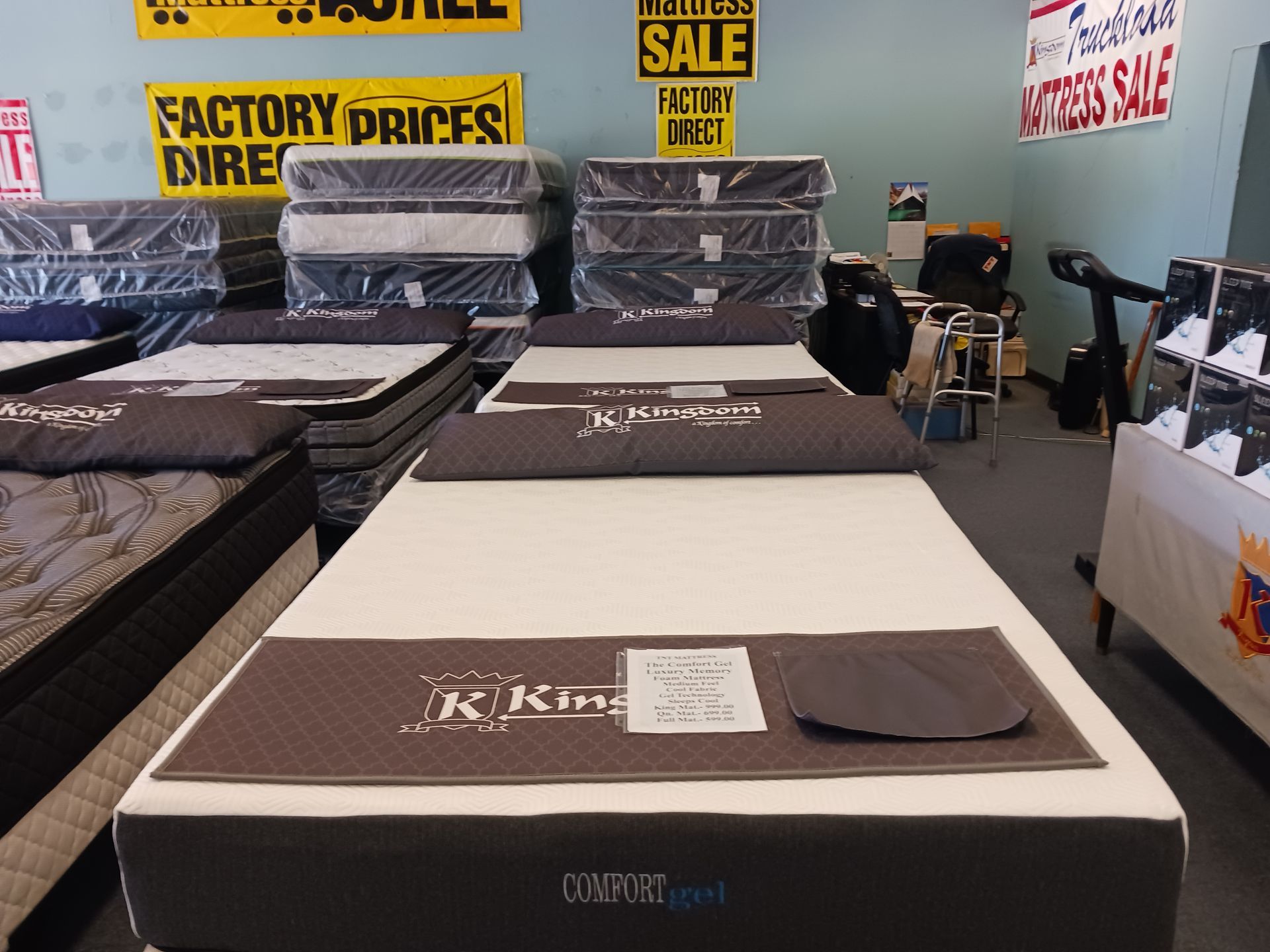 Mattresses are stacked on top of each other in a store with a sign that says factory prices direct