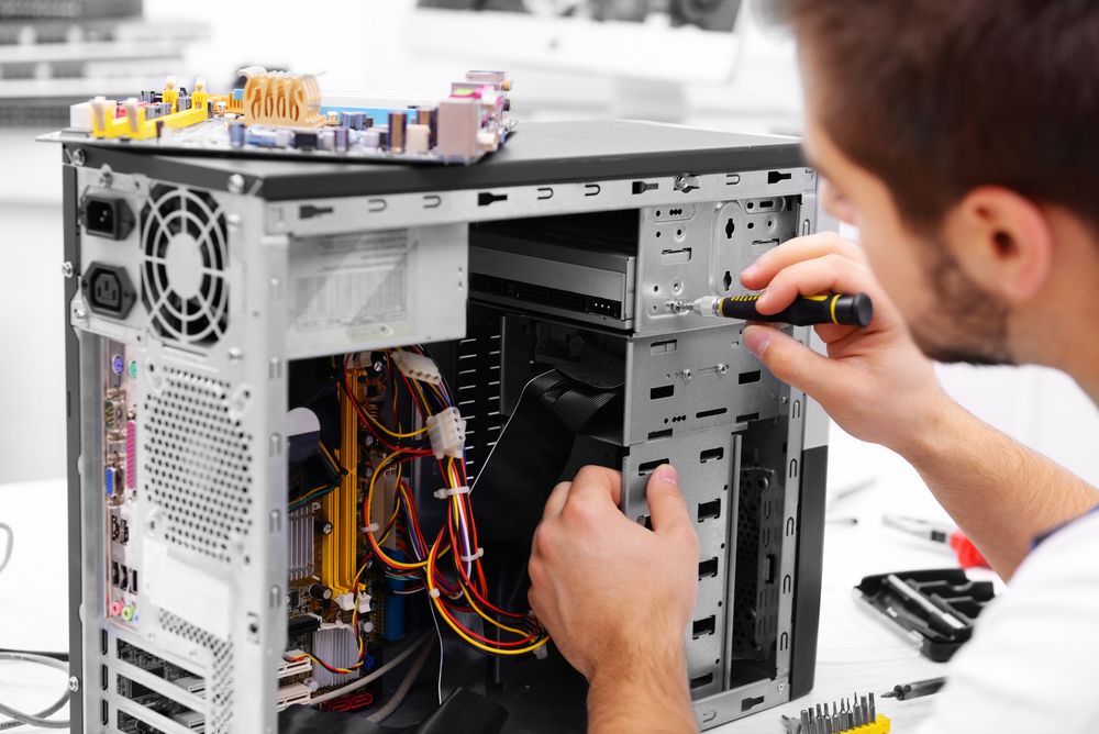 Man Repairs Computer Inside a Desktop Case with A Screwdriver — Rescuetech Computer And iPhone Repairs in Ballina, NSW