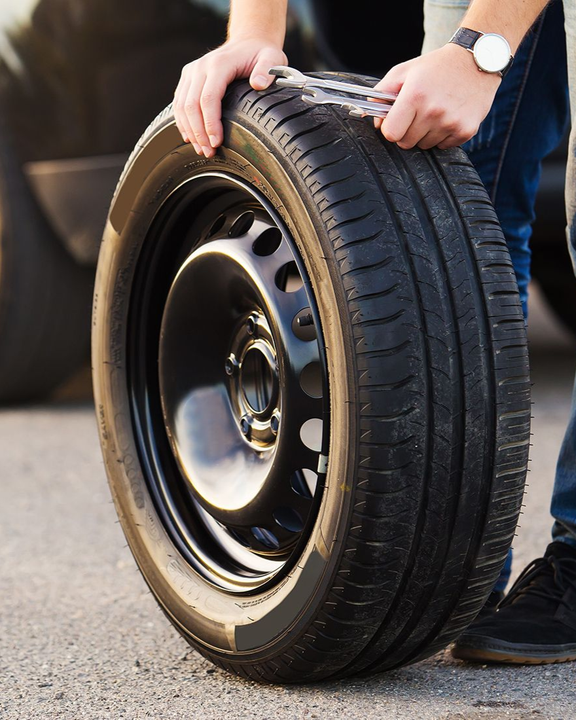 Gardener trimming a hedge with electric shears; wearing green cap, gloves, and overalls.