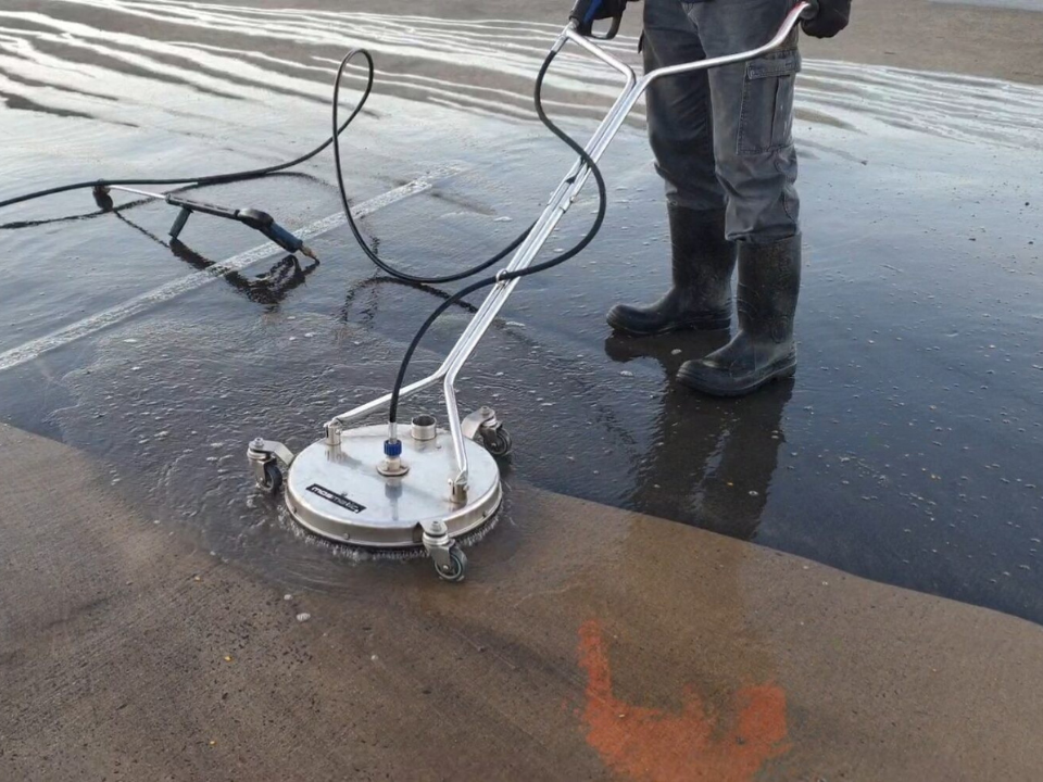 A person pressure washing a concrete surface. Before and after sections show the cleaning process.