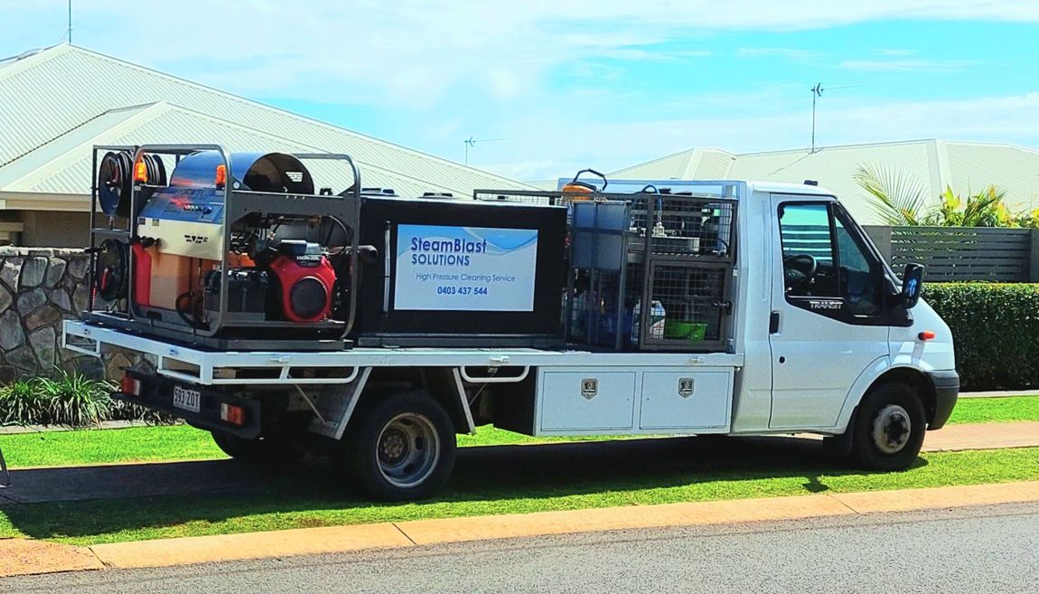 Two pickup trucks with cleaning equipment on the beds parked on green grass.