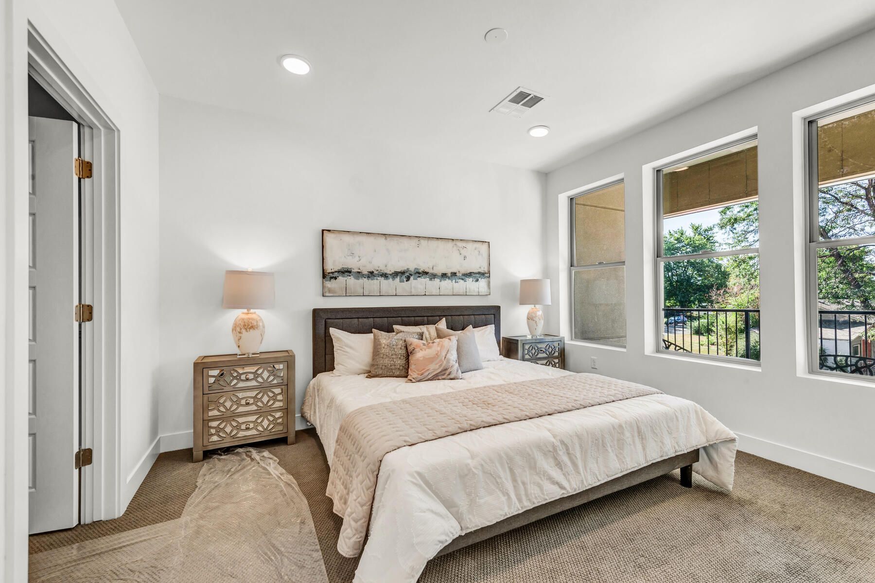 Bedroom with bed, nightstands, windows, and neutral color scheme.