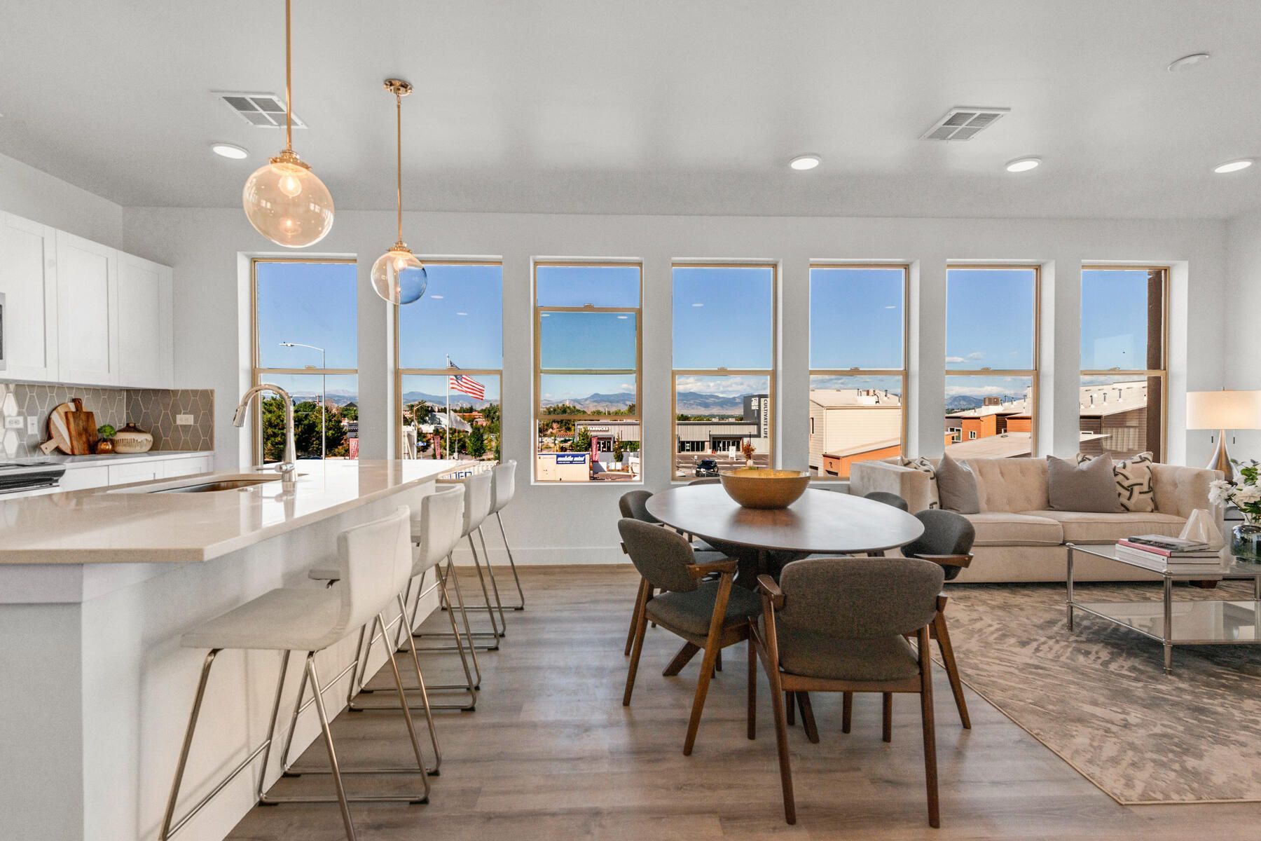 Bright open-concept living space with kitchen, dining area, and seating. Large windows offer city view.