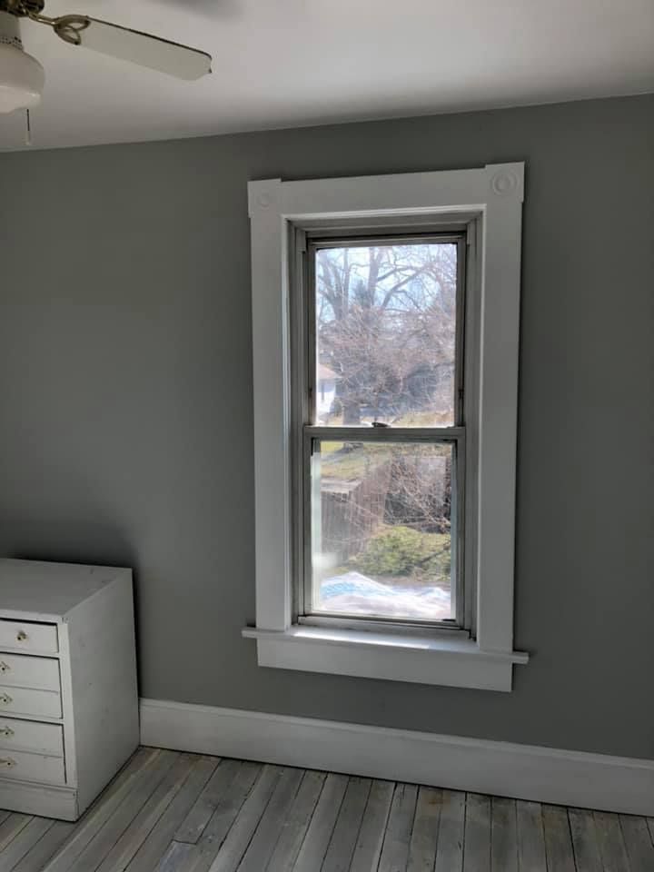 A bedroom with a window and a ceiling fan.