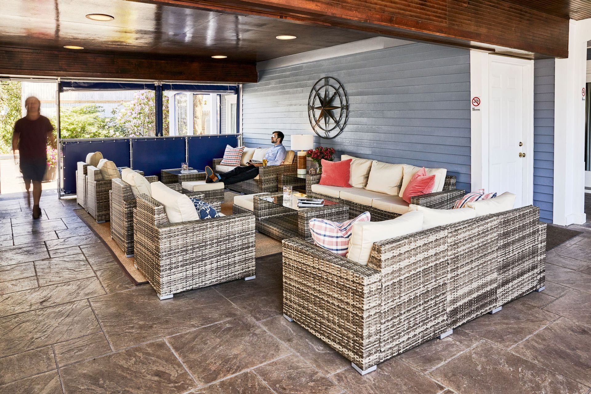 A man is sitting on a couch in a living room with wicker furniture.