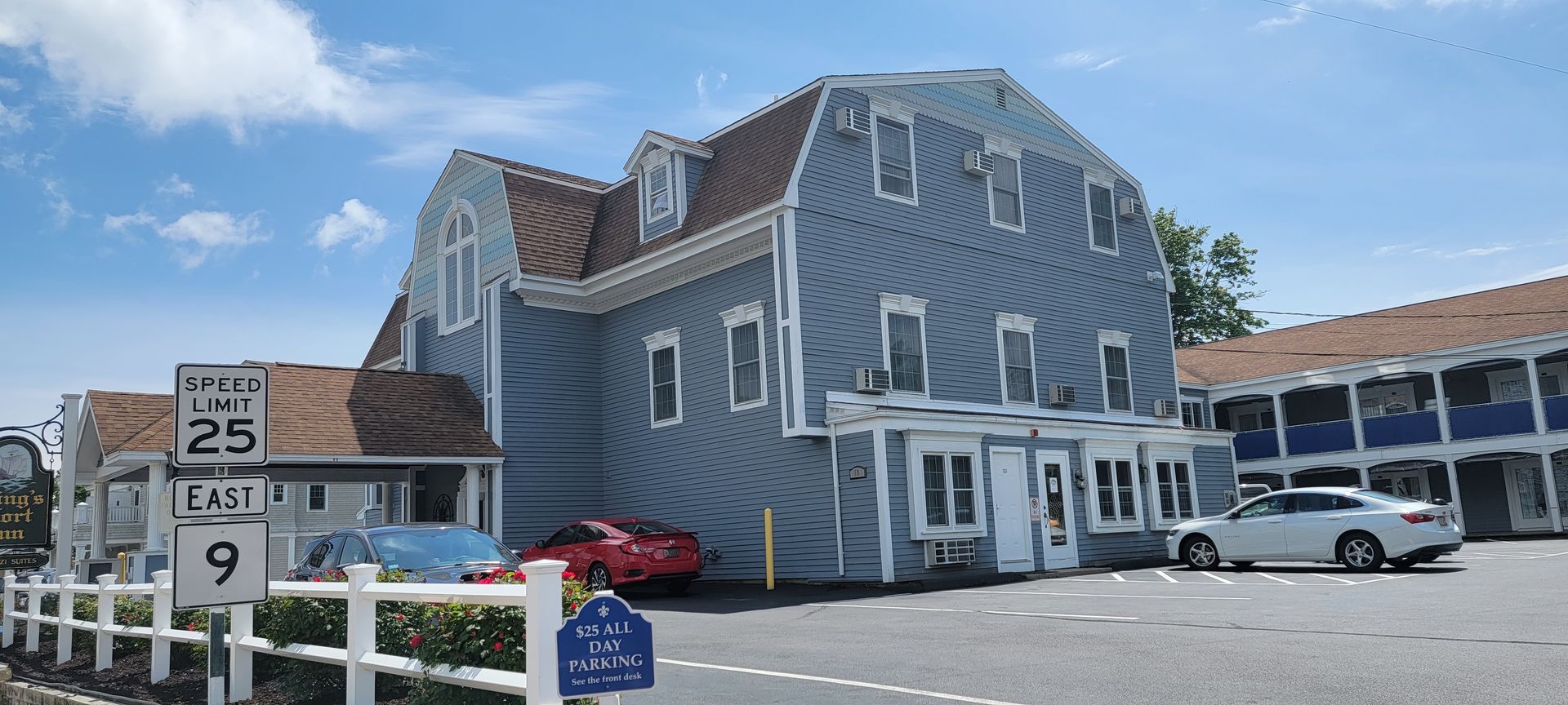 A motel with cars parked in front of it on a sunny day.