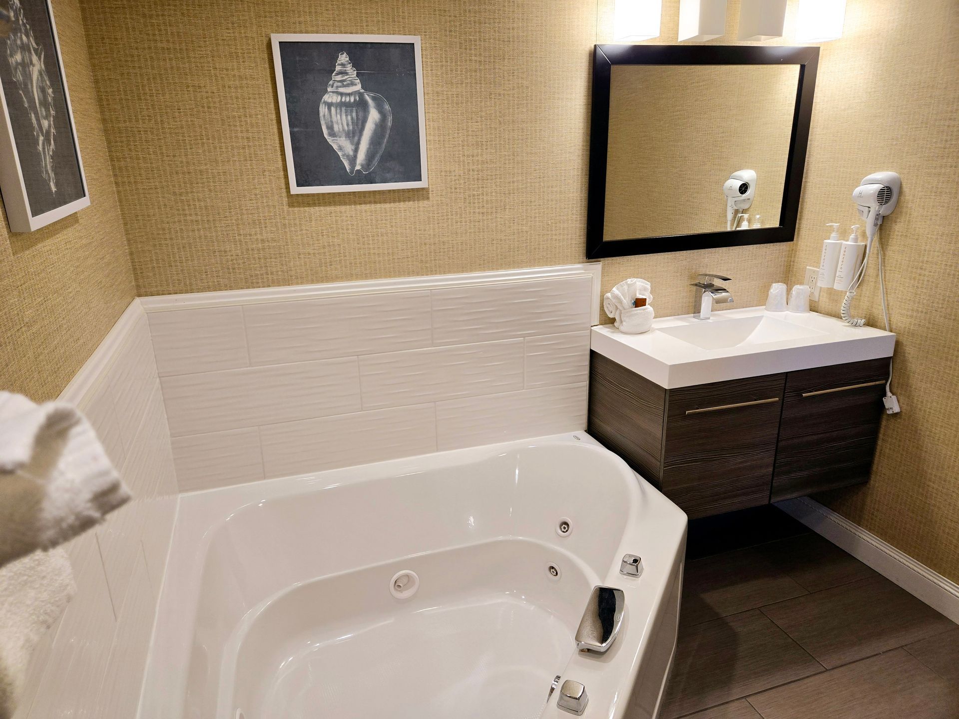 A bathroom with a jacuzzi tub , sink and mirror.