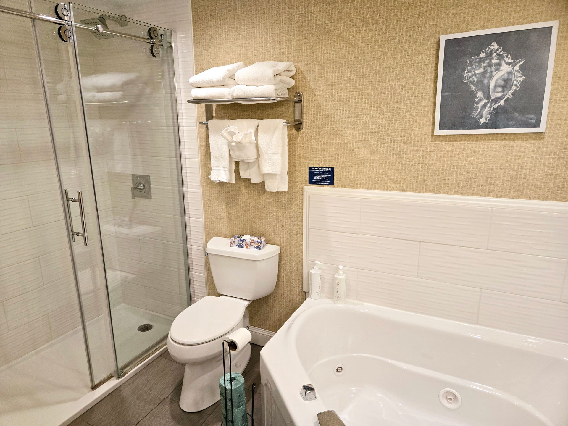 A bathroom with a toilet , tub , shower and picture on the wall.