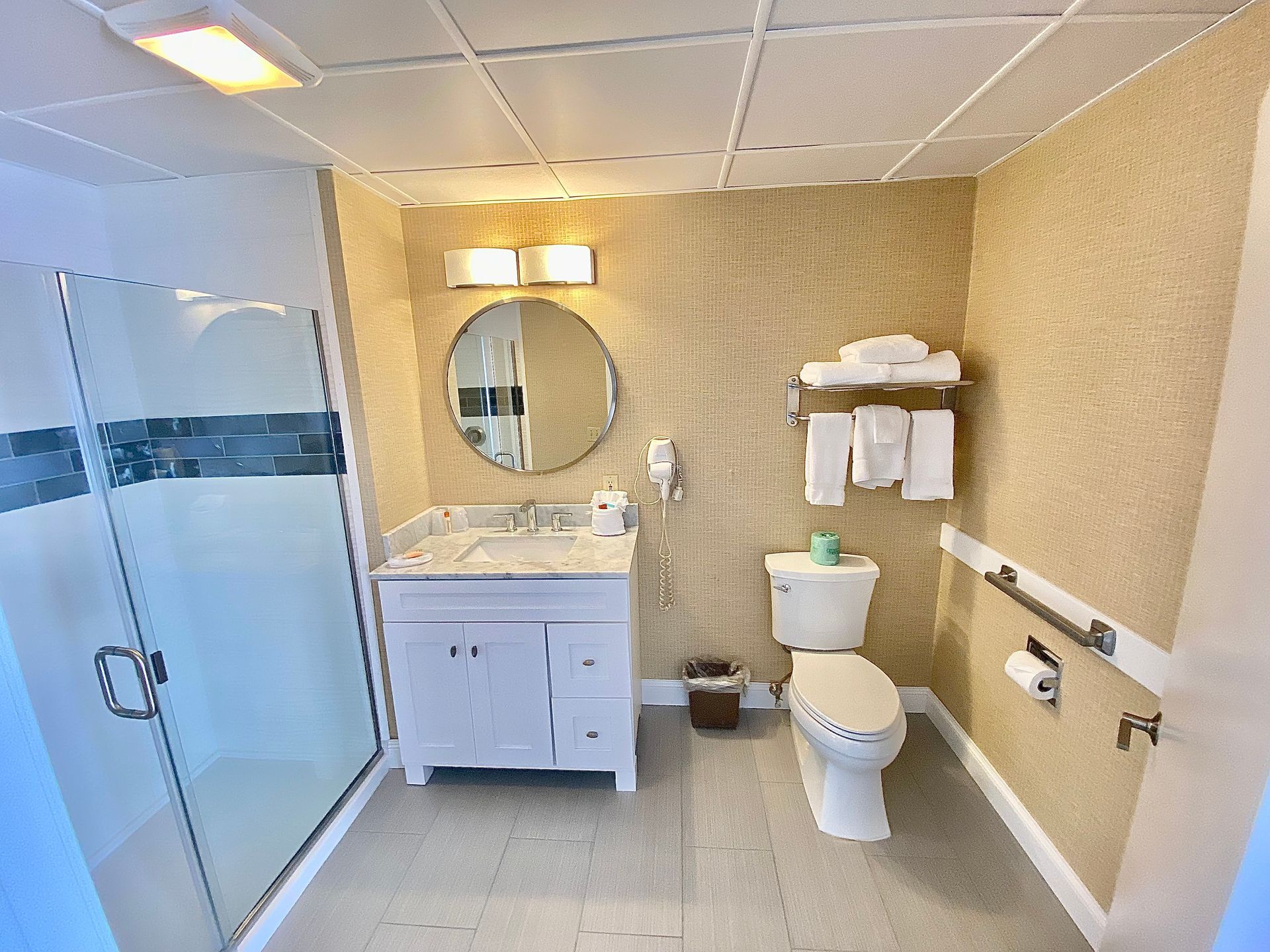 A bathroom with a toilet , sink , mirror and shower.