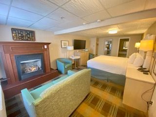 A hotel room with a king size bed , fireplace , couch and chairs.