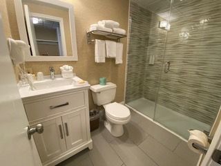 A bathroom with a toilet , sink , mirror and shower.