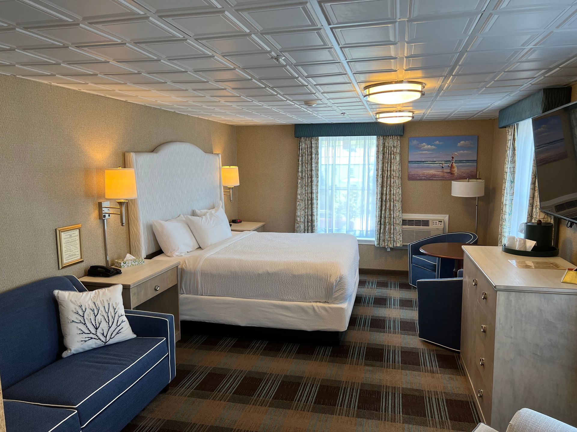 A hotel room with a bed , couch , dresser and television.