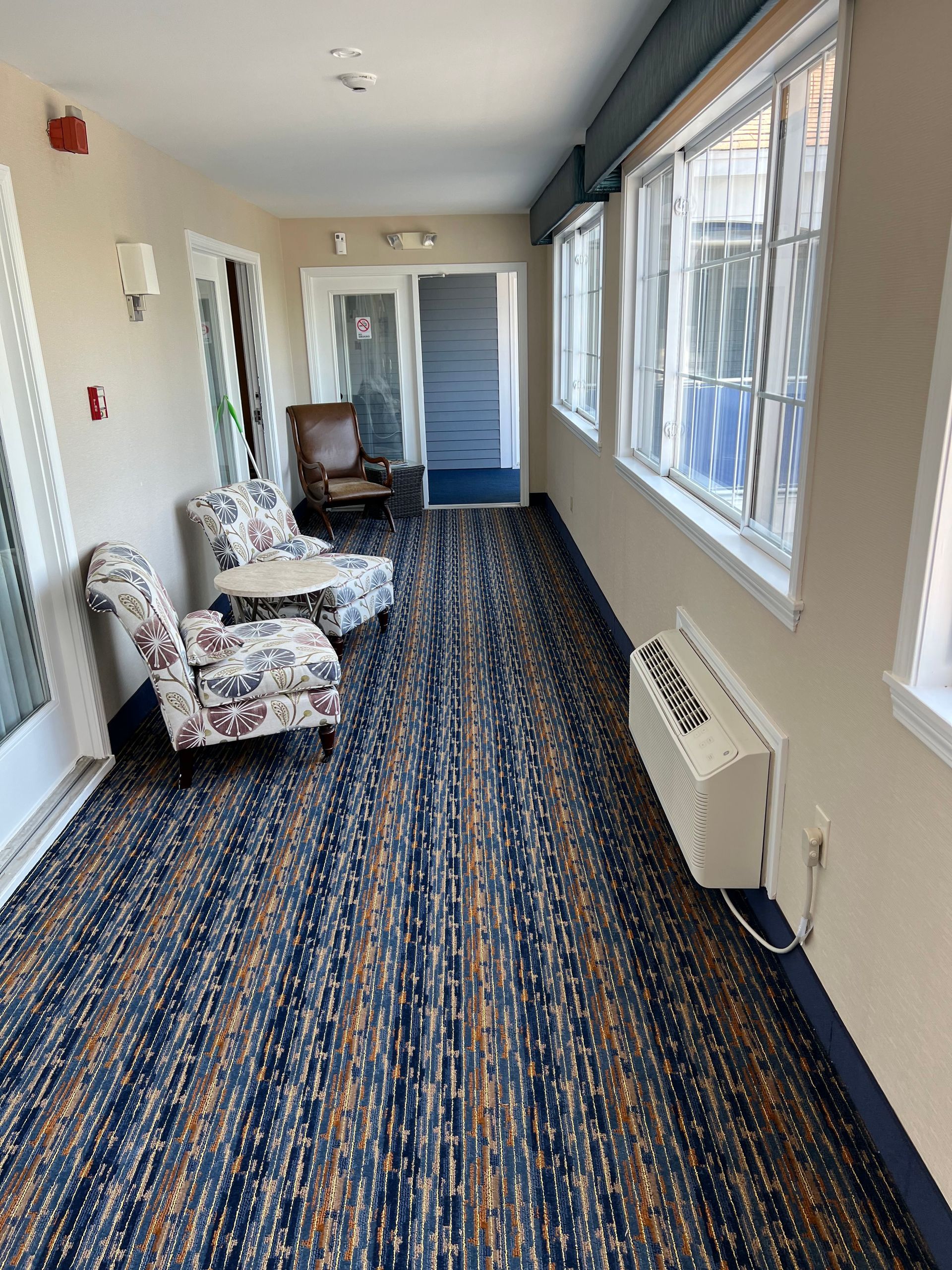 A long hallway with a lot of windows and chairs.