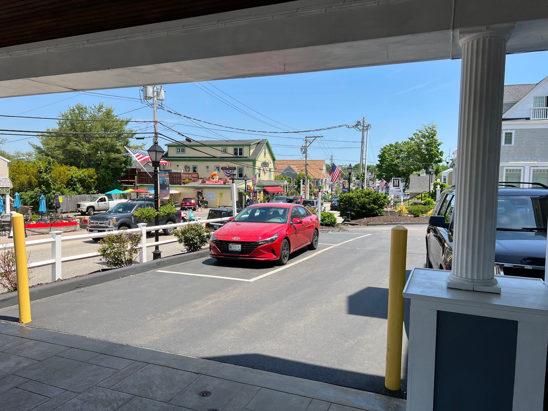 A red car is parked on the side of the road in a parking lot.