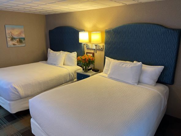 A hotel room with two beds and two lamps.