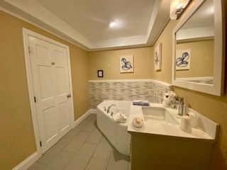 A bathroom with a tub , sink and mirror.