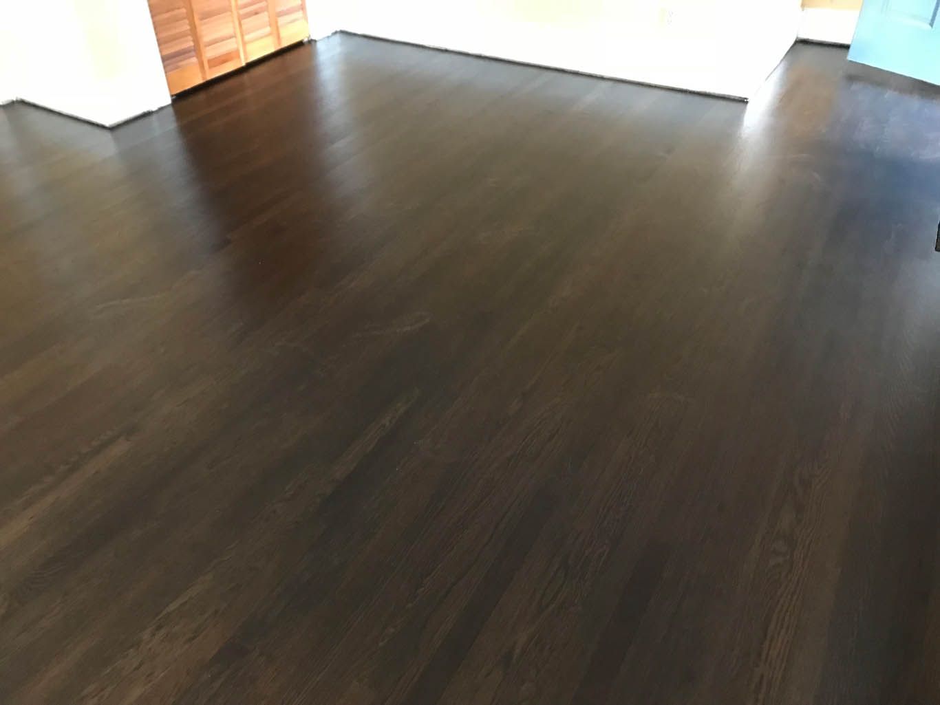 A room with a dark wooden floor and a white wall.