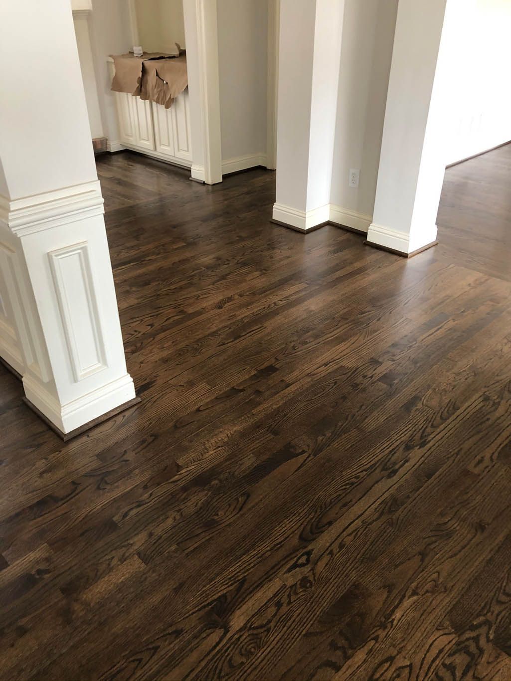 A living room with hardwood floors and white pillars.