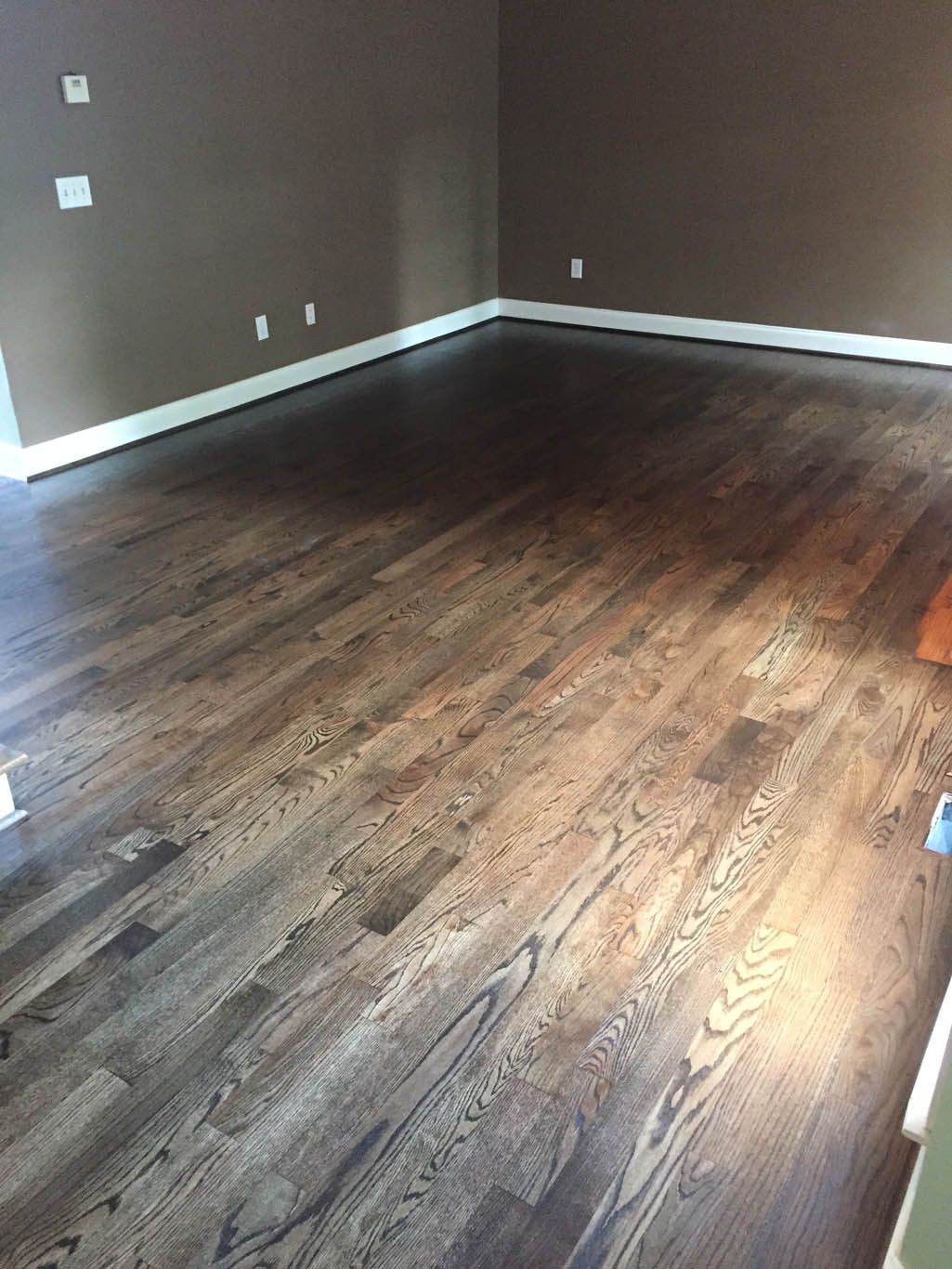 A living room with hardwood floors and brown walls.