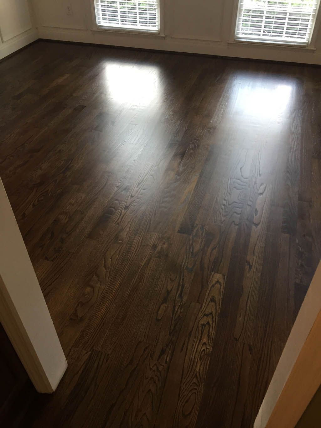 A living room with hardwood floors and two windows.