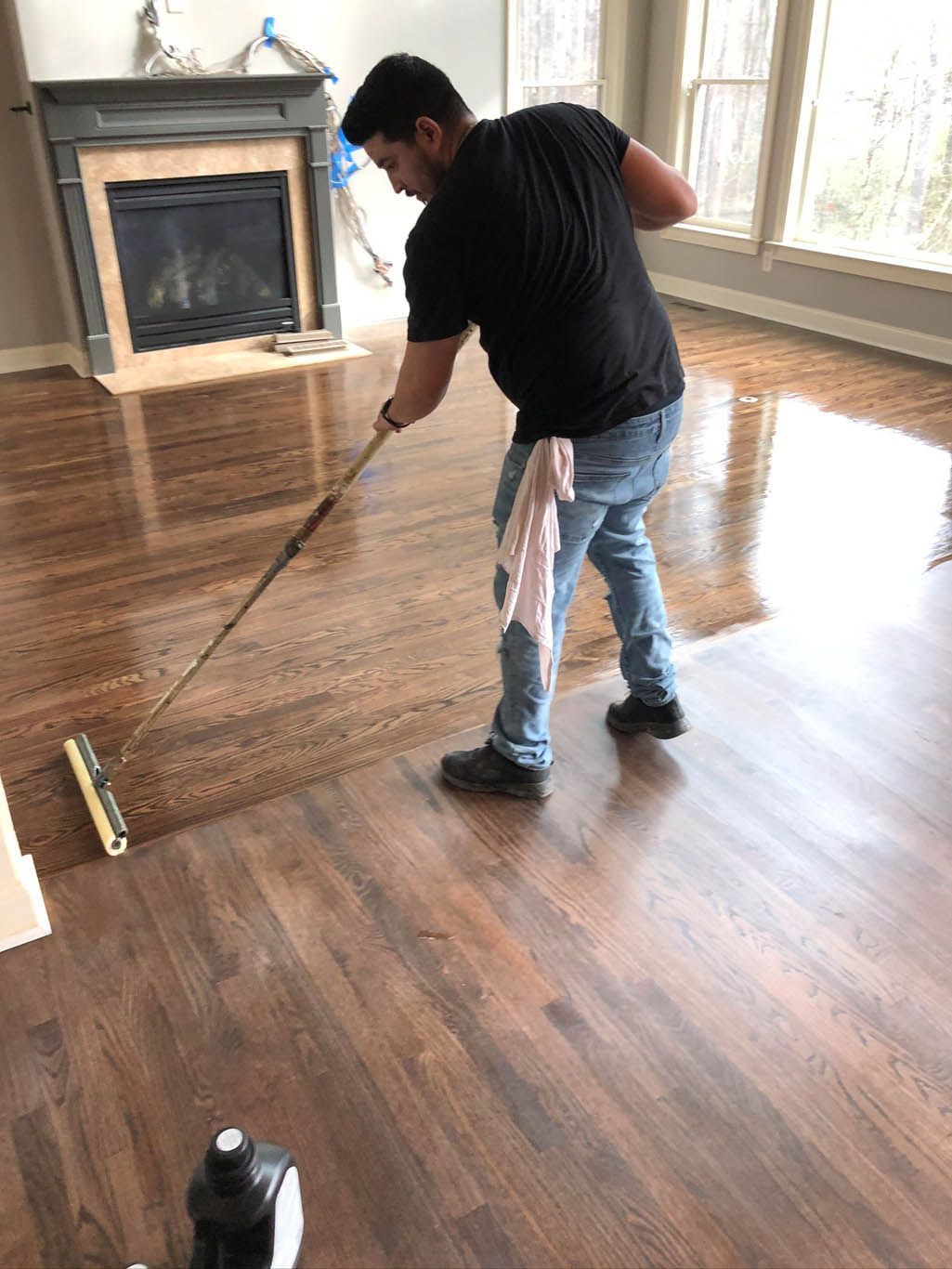 A man is polishing a wooden floor with a mop in a living room.