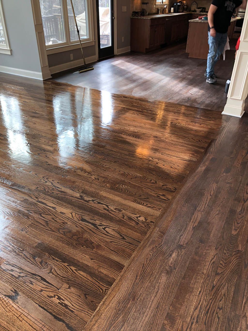 A man is standing on a wooden floor in a living room.